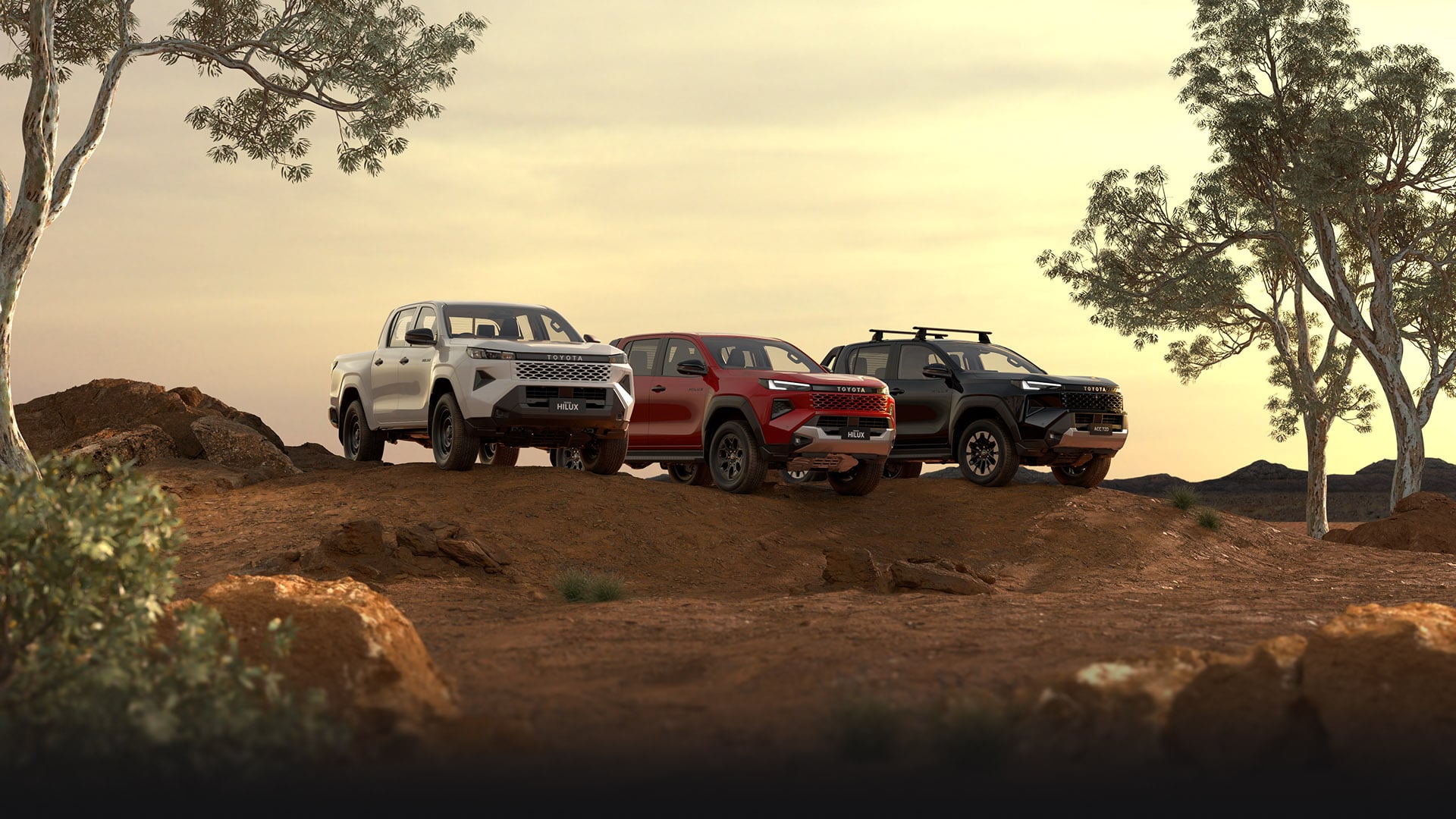 Three HiLux double-cab utes sit parked in a dirt clearing at golden hour. The first has Glacier White paint, the middle one is Feverish Red and the end one is Ash Slate. Australian trees and scrub frame the scene, while the sun sets behind them.