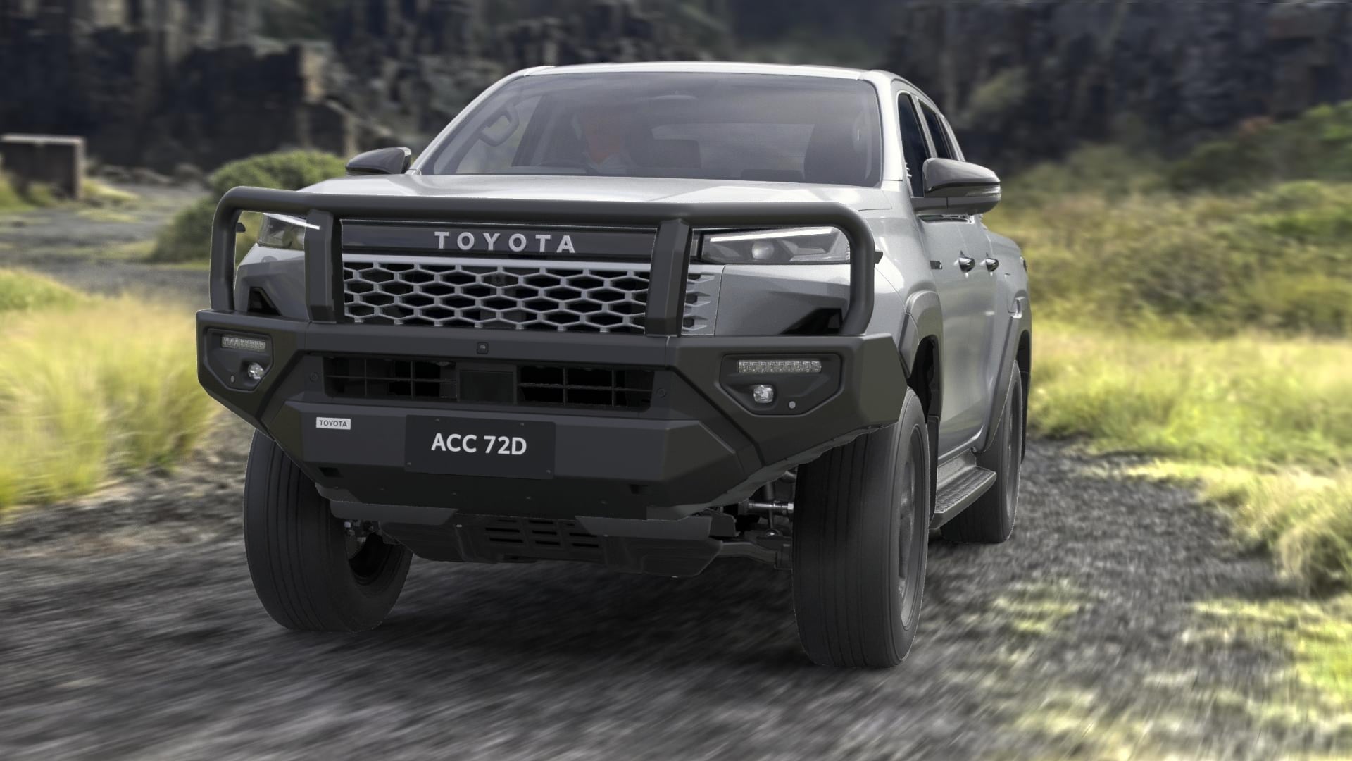 A Stunning Silver Toyota HiLux double-cab ute, fitted with a black Bull Bar, drives down an unpaved road. A slight motion blur conveys speed.